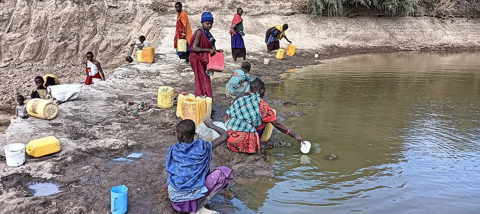 Women and children fetching water from a sand dam in Longido.