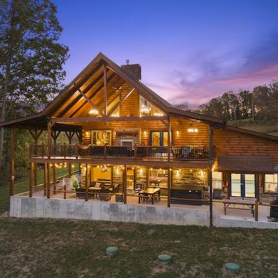 Large log cabin with multiple decks at sunset