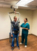 Woman ambulating usings a gait training sling and ceiling lift.