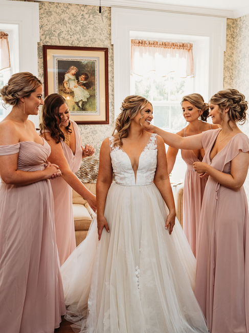 bride in an old Victorian house getting ready with her bridesmaids. beautiful white wedding gown and blush pink bridesmaid dresses.