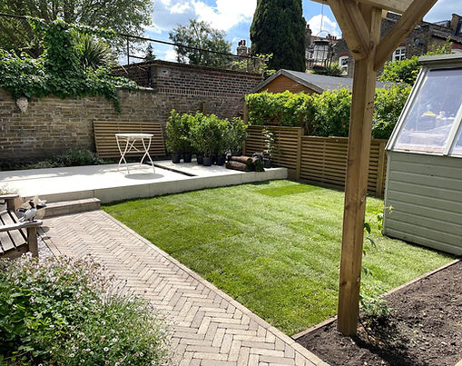 Looking from the new rose arch to the back of the garden, you see a bench on the left-hand side nestled in planting and a new patio space that is perfect for sunbathing and entertaining.