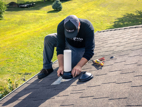 Contractor performing roof leak prevention by checking the flashing and seals around a roof penetration point.