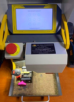 Key Machine with a key in the holding position with brass shavings and a business card attached to the machine with a combination password screen showing circles.