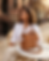 Here is the alt text for the image: **Alt Text:** A woman with wavy dark hair, wearing a white button-down shirt, sits at an
