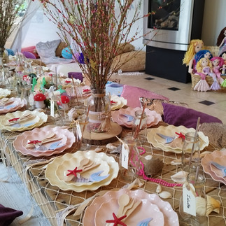 mermaid themed low wooden picnic table with fairy and mermaid decorations with a tipi in the back