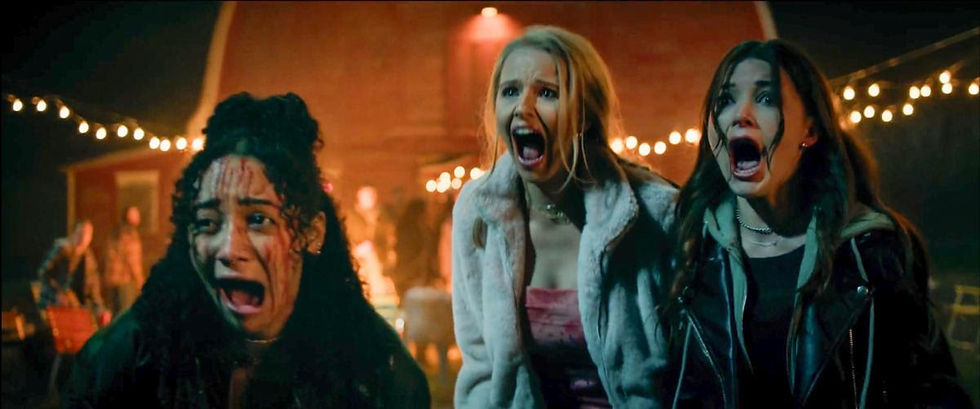 Three women are screaming in fear outside at night, surrounded by string lights and a barn. The scene is tense and dramatic.