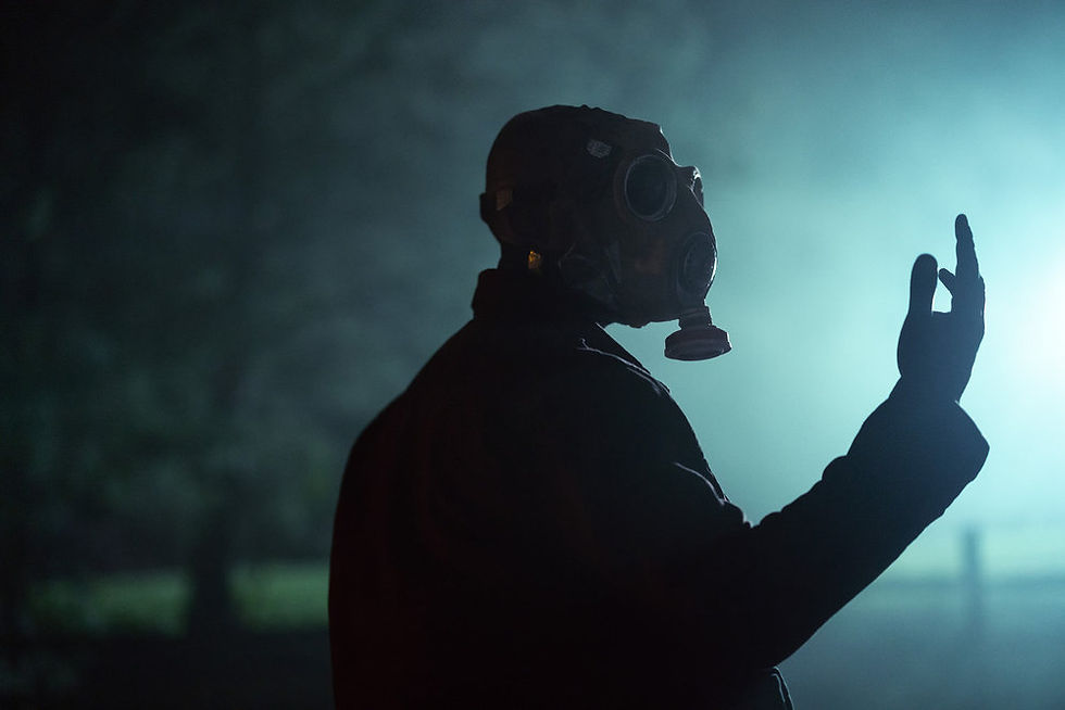 A man in a gas mask stares at his hand