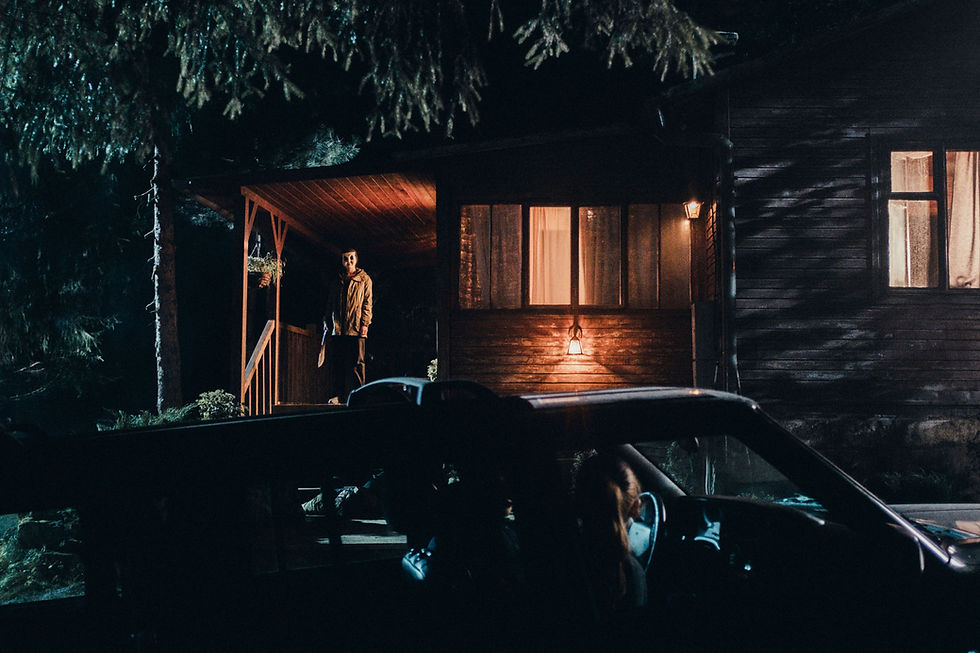 A masked person stands on the porch of someone's house