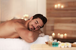 apuesto-joven-relajandose-en-la-mesa-de-masajes-en-el-espacio-del-salon-de-spa-para-texto.