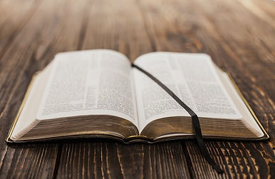 Open Holy Bible on wooden table with ribbon bookmark, symbolizing the Word of God, Scripture, truth, and Christian faith