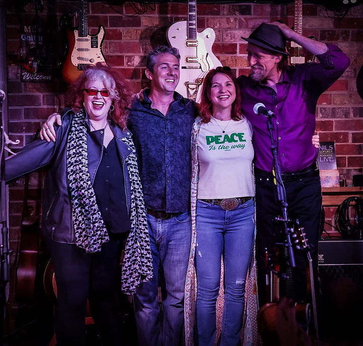 Loved for their strong vocal harmonies and driving rhythms, four piece The 19th Street Band delivers high-energy Americana, hillbilly, gypsy-rockin’ good time music that drives audiences mad. The band comprises Caolaidhe, pronounced “Cally”, Davis (guitar/harmonica/vocalist) alongside fiddle/mandolin/vocalist/partner-in-crime Meghan Davis, with Christopher Brown (bass/vocals) & Patty Dougherty (drums). Their songs touch the heartstrings, lift the spirits and remind us that life is just a beautiful mess.
Their newest album, Near Perfect, has received air play on radio stations throughout the UK, including BBC Radio and is receiving rave reviews from all the leading music magazines throughout the UK and Ireland. The album includes a recording of “Livin’ in These Troubled Times”, a song written by Philip Donnelly about the Troubles in Belfast and made a #1 hit by country artist, Crystal Gayle.
The 19th Street Band has entertained crowds at US festivals such as DelFest, Charm City Bluegrass Festival, National Cherry Blossom Festival, The Washington Folk Festival, Iowa Irish Festival, and Maryland Irish Festival. With roots just outside of Belfast in Holywood, the band has been featured as a regular artist at the Open House Festival in Bangor, Northern Ireland and the Dunmore East Bluegrass Festival in Co. Waterford. They tour Ireland/UK every year and bring 40+ American fans along for the ride. This year they will be rocking their ‘Baps to Baguettes’ Tour from Belfast to France.