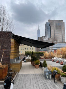 black modern awning in the late fall on a rooftop outdoor living space in NYC with The Freedom Tower in the background.