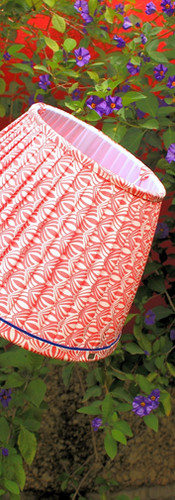 abajur franzido estampado em tom salmão com fita azul, num jardim