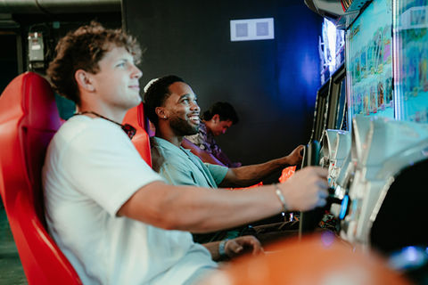 Friends playing racing game in arcade.