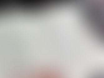 Open book on a table with text showing chapter six. A hand with teal nail polish holds a page. A pink mug with a sloth design sits nearby.