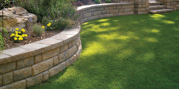 Sandstone retaining wall dividing a garden and backyard turf on different levels. The backyard is in Ferntree Gully