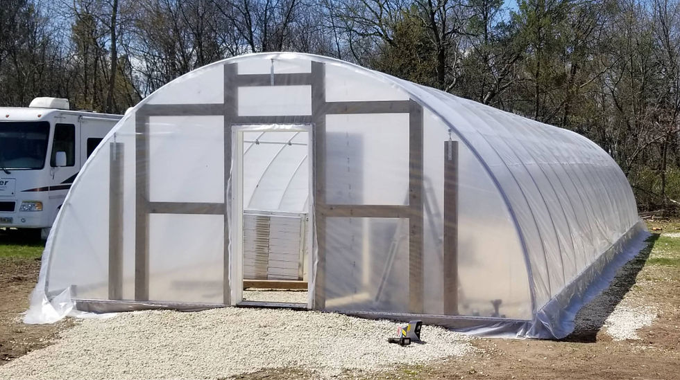 High tunnel greenhouse exterior showing hoop house layout and gravel base.