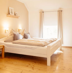 Gemütliches Doppelbett aus Holz in einem lichtdurchfluteten Schlafzimmer der Unterkunft Schwalbennest, Victorhof