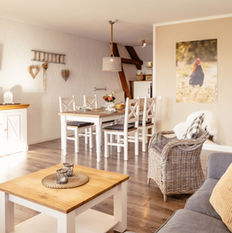 Blick aus dem Wohnzimmer auf den hellen Essplatz mit weißen Stühlen in der Ferienwohnung Schwalbennest, Eifel