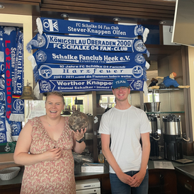 Die Workshop Koordinatorin Eva von Schalke-macht-Schule steht mit Lion hinter der Theke in der Veltins-Arena