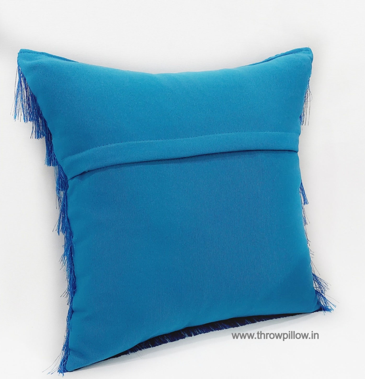 "Luxurious teal blue cushion cover with fringe detail"