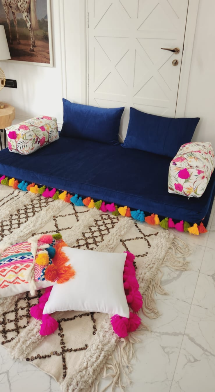 Eye-level view of a floor seating area with layered cushions and mattress covers in soft earth tones
