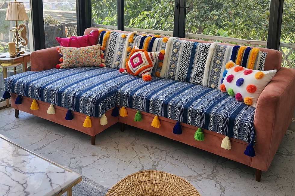 Eye-level view of blue tribal printed sofa cover with multicolor tassels on a wooden sofa in a living room