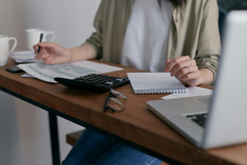 Woman sitting at a desk calculating numbers with a calculator