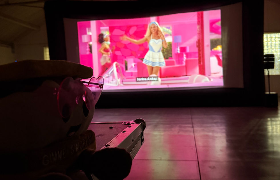 Wide angle view of an outdoor movie screen set up in a park at dusk