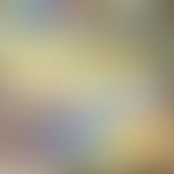 Kreatives Arbeietsplatz mit Aquarellfarben, Laptop, eine Tasse KaffeePinseln in einer Tasse und einem Notizbuch auf einem Tisch - im Hintergrund ein heller Raum mit Alltagselementen.