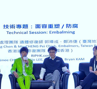 CHENG Man Hon, Nick in a bright green suit speaking into a microphone while seated on a panel at the AFE under a screen reading "Technical Session: Embalming."