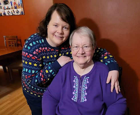 Two women smiling together, one in a patterned sweater.