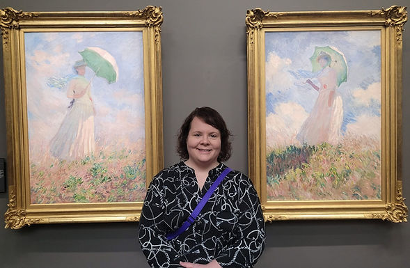 Woman standing between two Monet paintings of women with parasols.