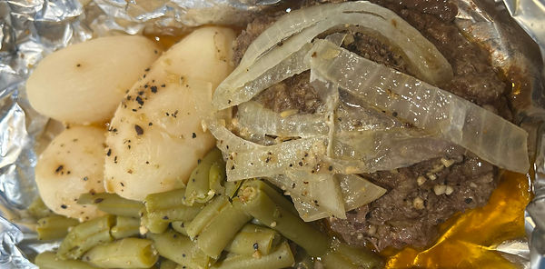 Homemade TV dinner with beef, onions, potatoes, and green beans in foil