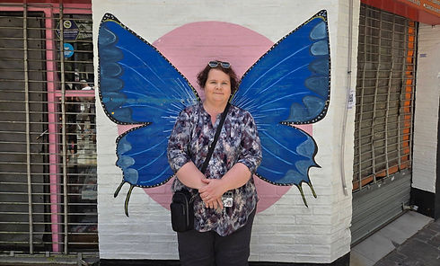 Woman standing in front of large blue butterfly street art