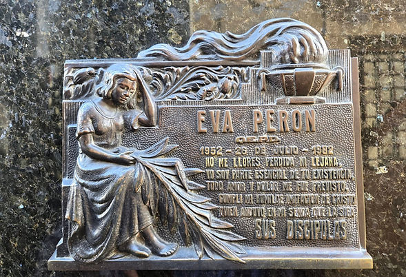 Memorial plaque of Eva Perón with a seated figure and torch.