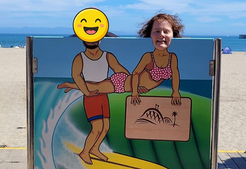 Girl posing in a surfing photo cutout board at a beach