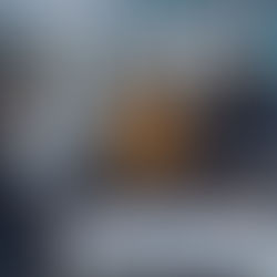 A woman shows papers to a thoughtful couple on a gray sofa in a living room decorated with blue accents and framed photos.