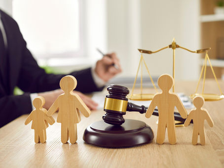 A group of wooden figures making up a family at the forefront with a gavel in between