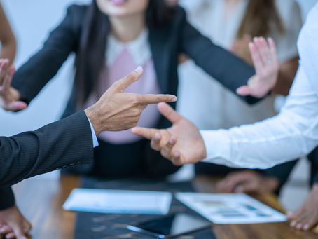 Two people arousing with each other and someone with their hands out to calm the situation