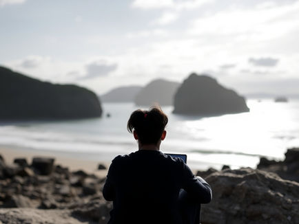 A visually calm and balanced image. A person sits peacefully, perhaps meditating or reading a physical book, with a smartphone placed respectfully to the side, perhaps in a "do not disturb" mode or turned off. Soft, warm light fills the scene. The background is uncluttered, suggesting mental clarity. Elements of nature (a small plant) might be present. The overall mood is serene and focused, symbolizing liberation from digital distractions.