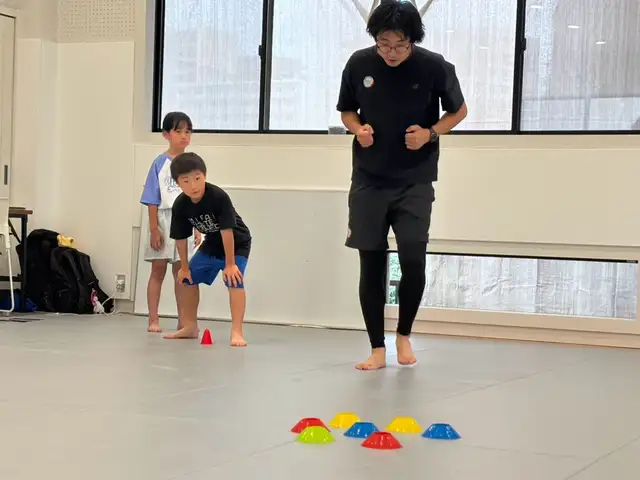 カラーコーンを使ったトレーニングで見本を見せるコーチ（滋賀南草津校）