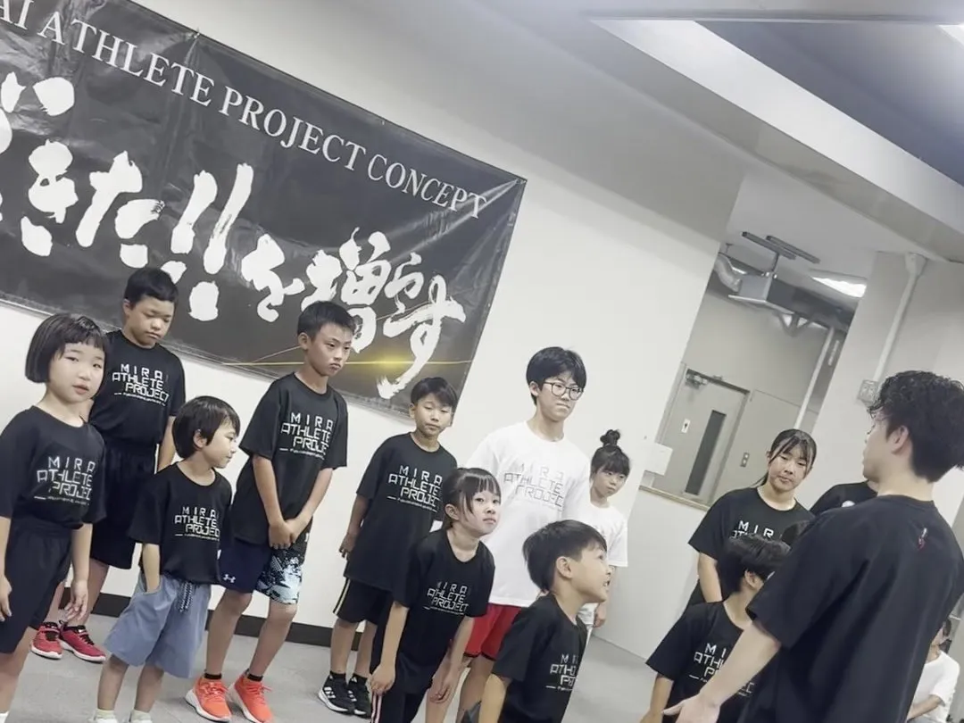 「できた!!を増やす」の横断幕の前に並ぶスクール生