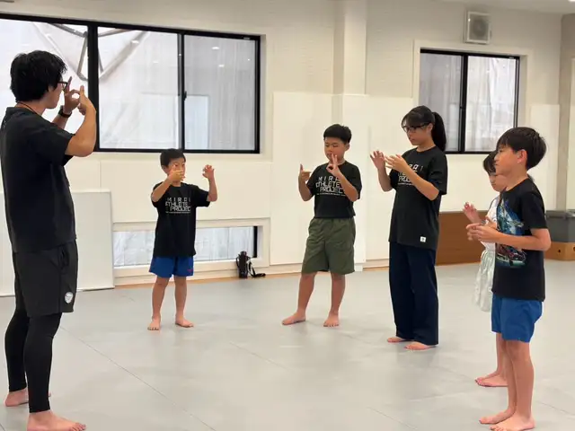 コーチの手の動きをまねてリズムトレーニングをする子どもたち（滋賀南草津校）