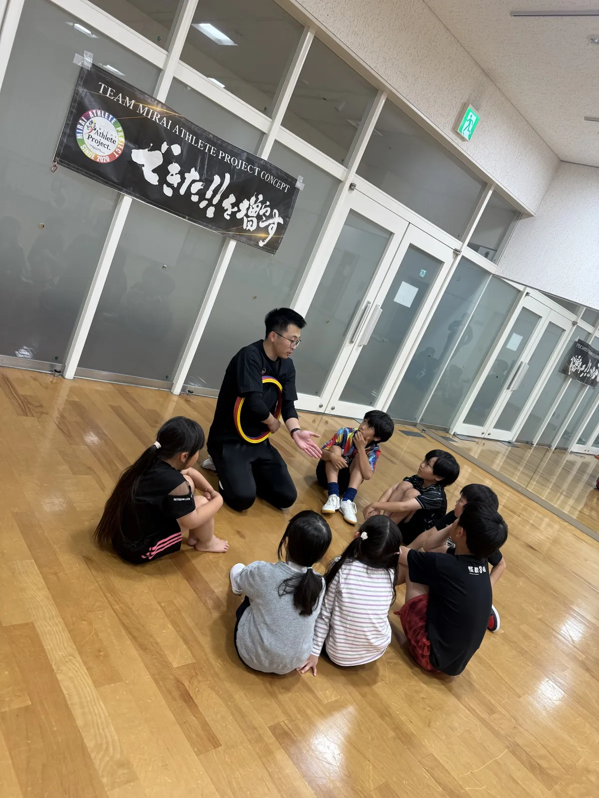 輪になってコーチの話を聞く子どもたち