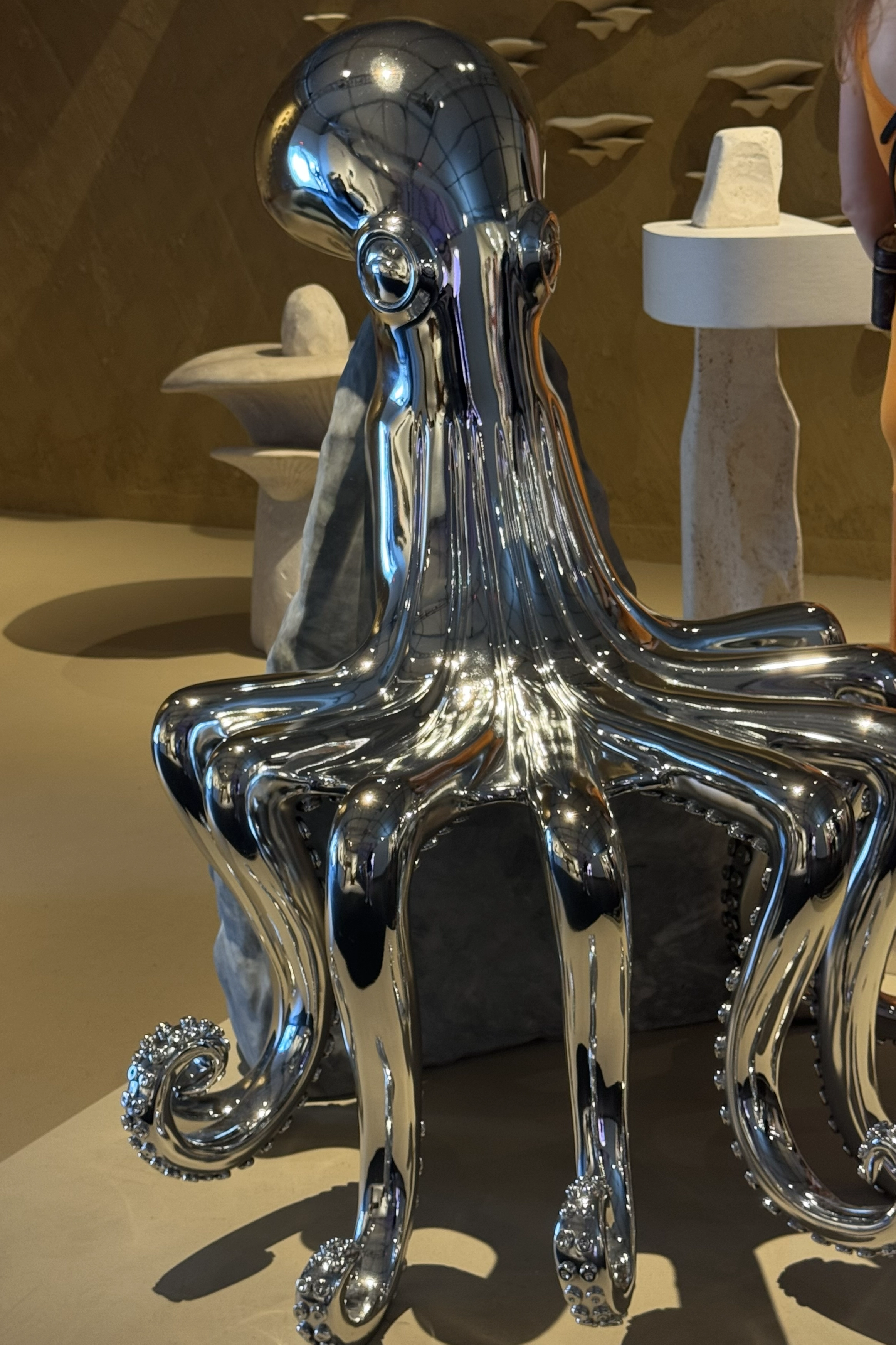 Chrome octopus-inspired sculptural object presented as collectible design in an exhibition setting.