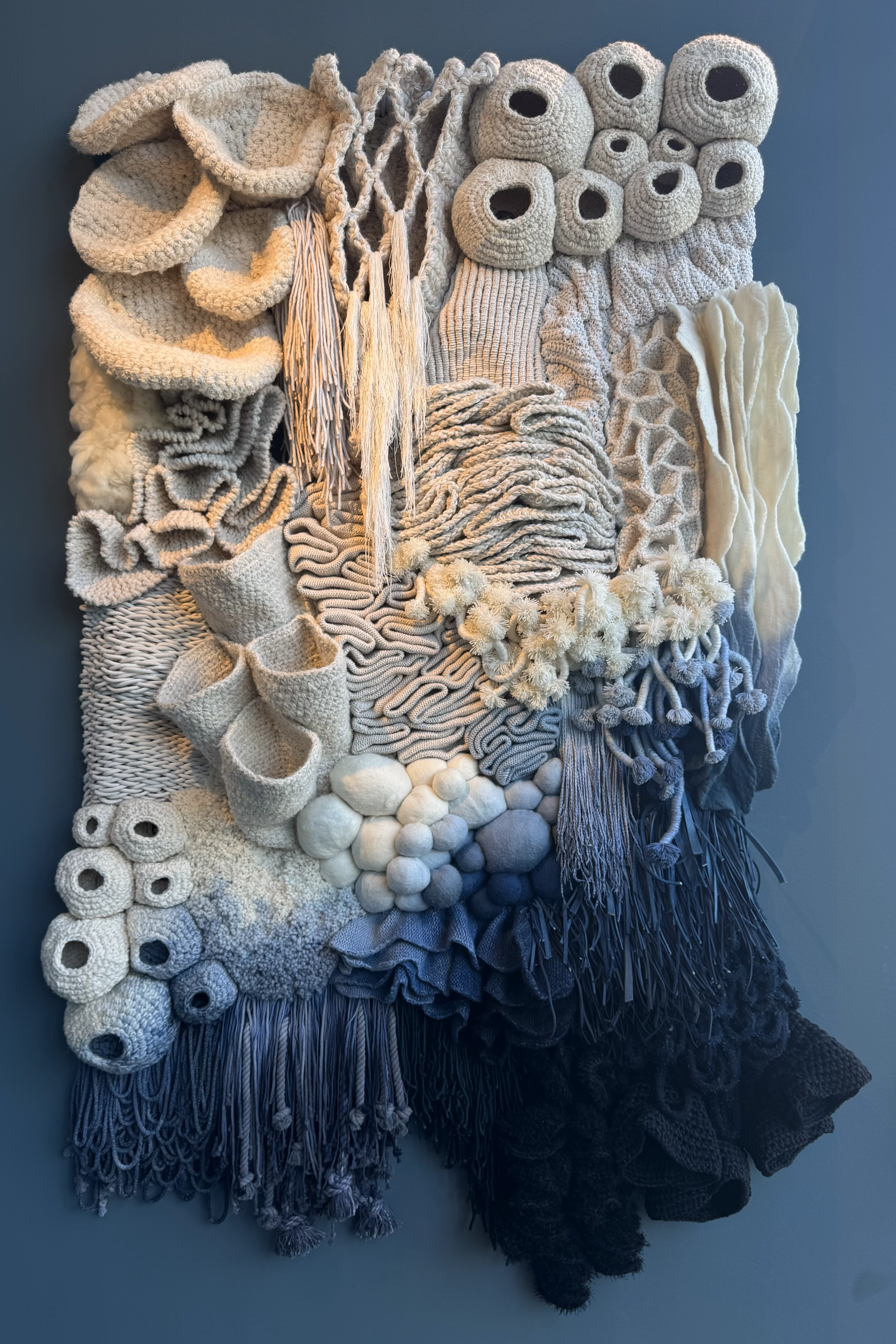 Textile wall installation with layered, hand-crafted textures inspired by coral reefs and organic marine forms.