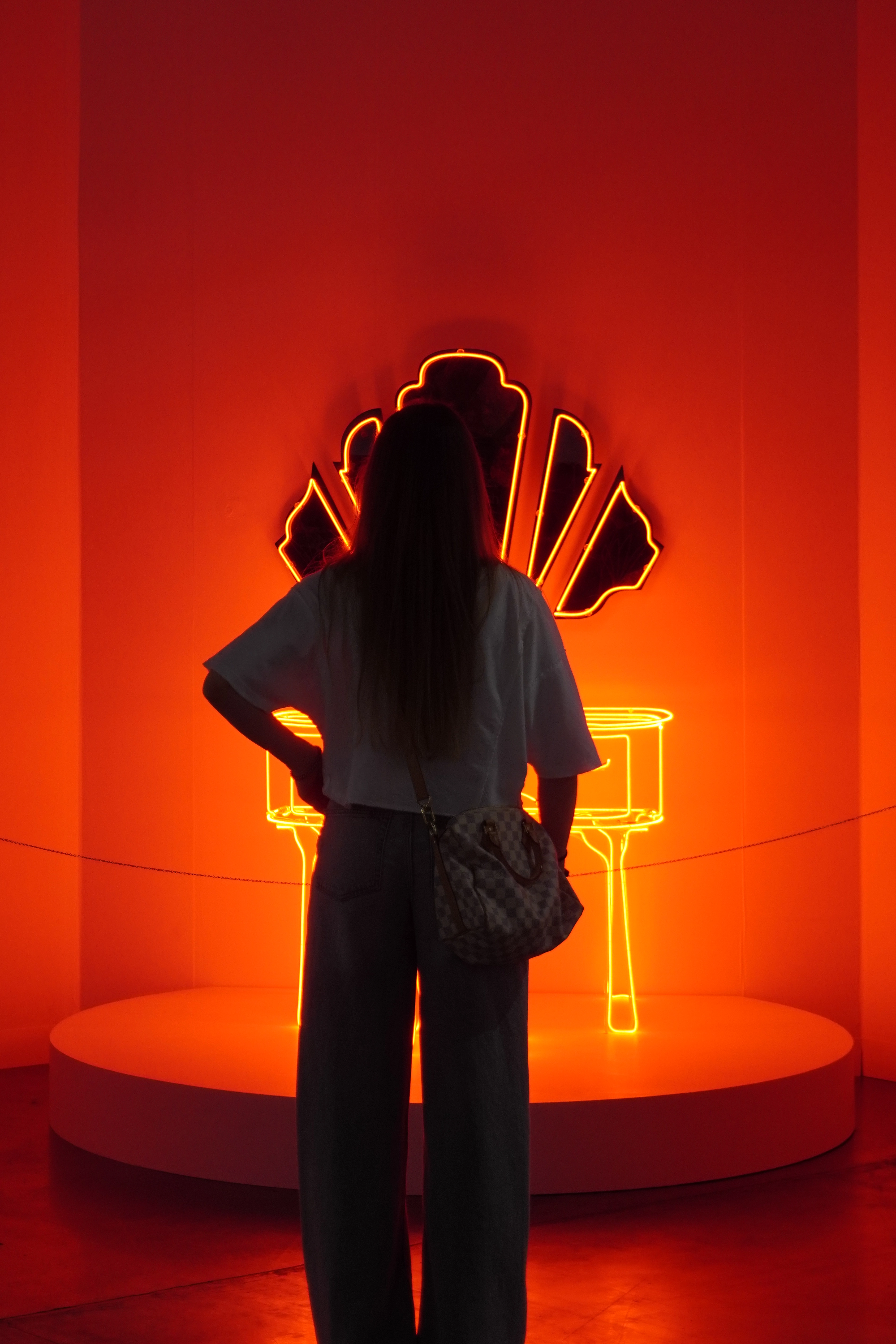 Red immersive installation featuring neon sculptural outline and monochromatic architectural backdrop at a design exhibition.