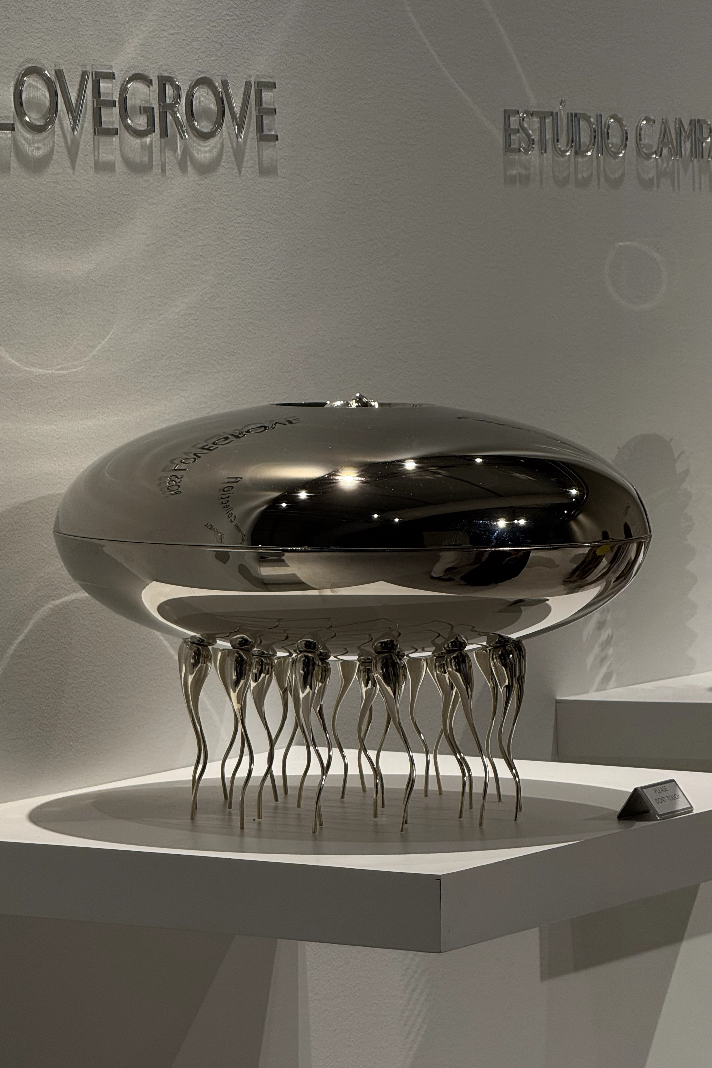 Chrome biomorphic collectible design object inspired by marine forms, displayed in a contemporary design exhibition.