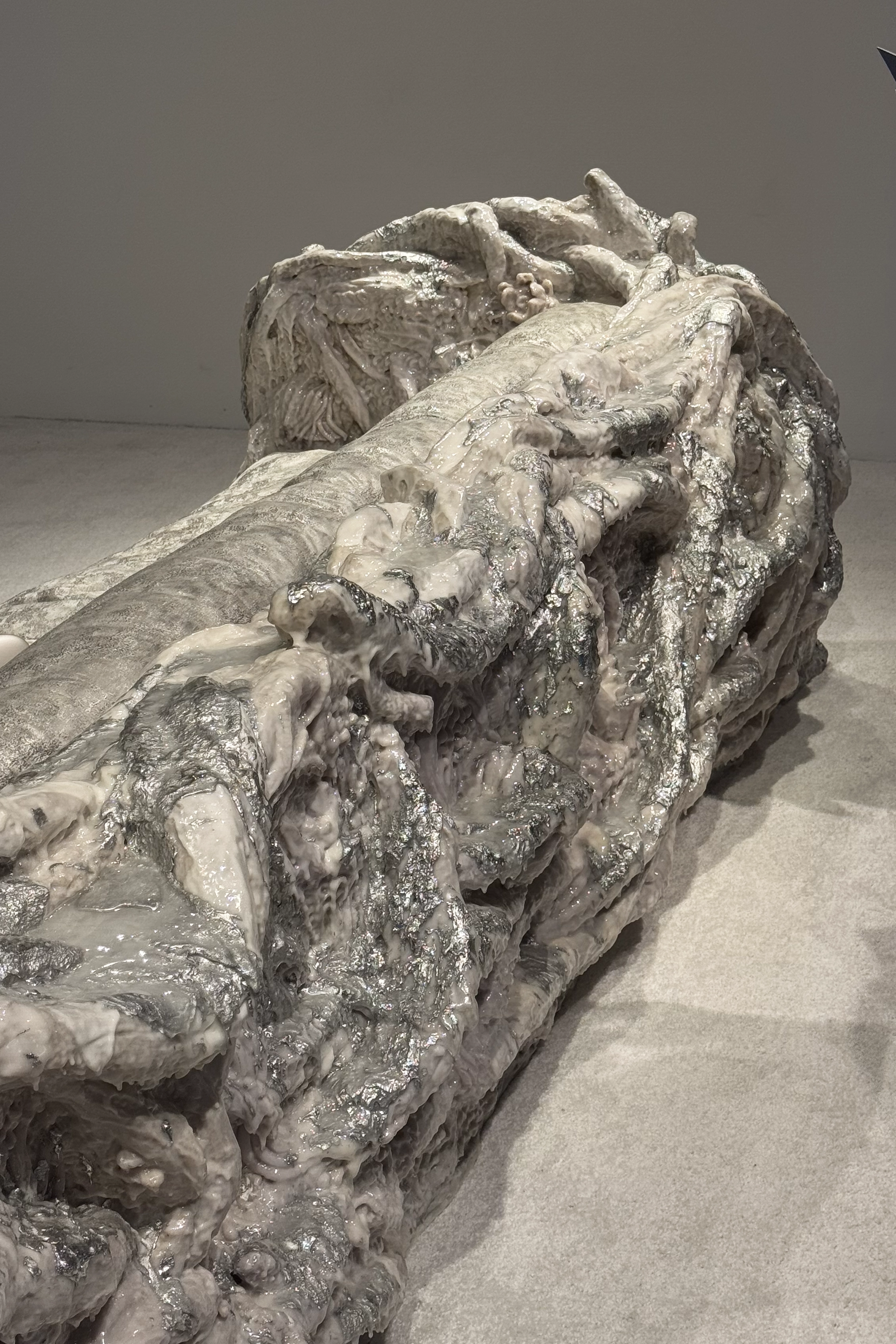 Large organic sculpture with metallic and soft layered textures, resembling geological or biological formations.